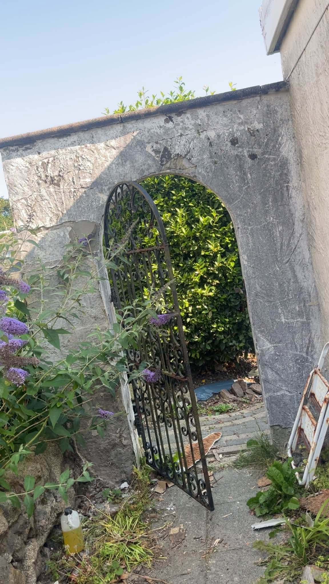 Old stone garden wall and ironwork gate before removal